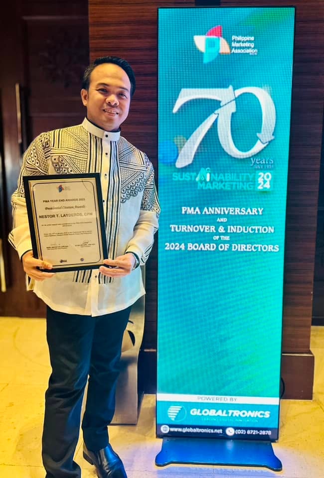 Sir Next poses with his PMA Year End Awards 2023 Presidential Citation Award beside the PMA anniversary display.